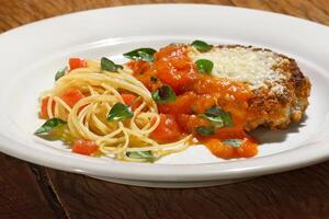 filé al parmigiano com espaguete com picado tomates foto