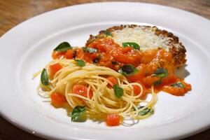 filé al parmigiano com espaguete com picado tomates foto