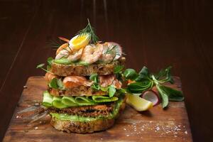 Smorgastarta, sueco sanduíche com peixe, maionese, ovos, fatiado pepino, defumado atum e camarão em centeio pão foto