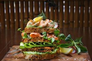 Smorgastarta, sueco sanduíche com peixe, maionese, ovos, fatiado pepino, defumado atum e camarão em centeio pão foto