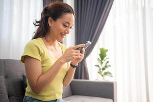 mulher usando inteligente telefone e navegando Internet às casa foto