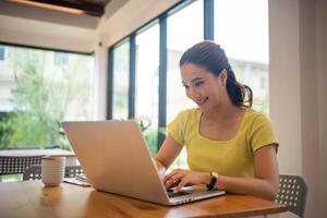 mulher sentado trabalhando com computador portátil às café comprar, freelance mulher trabalhando lado de fora conceito. foto