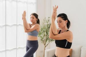 uma jovem em forma mulher práticas ioga de fazendo asanas dentro uma brilhante ioga estúdio. ioga praticante com alunos dentro ioga aula. foto