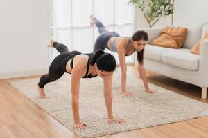 uma jovem em forma mulher práticas ioga de fazendo asanas dentro uma brilhante ioga estúdio. ioga praticante com alunos dentro ioga aula. foto