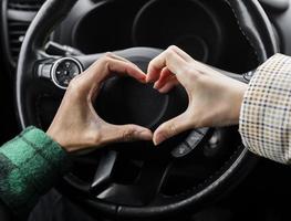 casal jovem viajando de carro fecha fazendo formato de coração foto