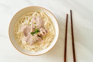 macarrão udon com carne de porco em sopa clara foto