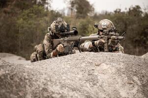 soldados dentro camuflar uniformes visando com seus rifles prontos para fogo durante militares Operação dentro a deserto soldados Treinamento dentro uma militares Operação foto