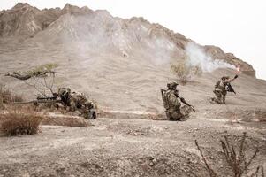 soldados dentro camuflar uniformes visando com seus rifles prontos para fogo durante militares Operação dentro a deserto soldados Treinamento dentro uma militares Operação foto