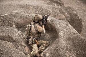 soldados dentro camuflar uniformes visando com seus rifles prontos para fogo durante militares Operação dentro a deserto soldados Treinamento dentro uma militares Operação foto