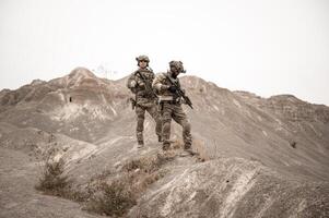 soldados dentro camuflar uniformes visando com seus rifles prontos para fogo durante militares Operação dentro a deserto soldados Treinamento dentro uma militares Operação foto