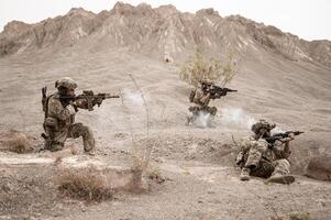 soldados dentro camuflar uniformes visando com seus rifles prontos para fogo durante militares Operação dentro a deserto soldados Treinamento dentro uma militares Operação foto