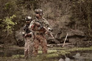 soldados dentro camuflar uniformes visando com seus rifles prontos para fogo durante militares Operação dentro a floresta soldados Treinamento dentro uma militares Operação foto