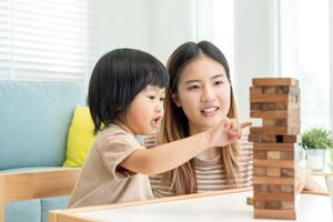 Ásia feliz solteiro mãe jogando Aprendendo jogos janga com a pequeno garoto. engraçado família é feliz e animado dentro a casa. pai e filho tendo Diversão gastos Tempo junto. feriado, fim de semana, vago. foto