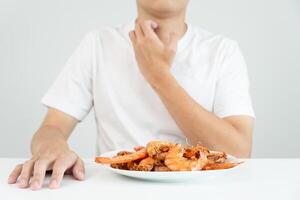 Comida alergias, homens ter reações comichão e vermelhidão depois de comendo camarão, frutos do mar alergia, coceira, irritação na pele, abdominal dor, diarréia, peito aperto, inconsciência, morte, forte evitar alergias foto