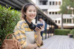 retrato lindo ásia mulher estudante. sorrir menina feliz estudar. usar telefone ler ebook dentro Faculdade campus. jovem fêmea em internacional Ásia universidade. Educação, estudar, escola, aprendizado, exame foto