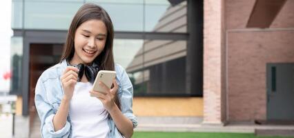 retrato lindo ásia mulher estudante. sorrir menina feliz estudar. usar telefone ler ebook dentro Faculdade campus. jovem fêmea em internacional Ásia universidade. Educação, estudar, escola, aprendizado, exame foto