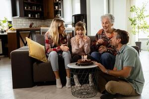 feliz família a comemorar avós aniversário com bolo dentro uma acolhedor vivo quarto foto