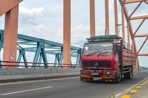 a velho vermelho mercedes benz caminhão cruzes uma concreto arco ponte, Indonésia, 16 janeiro 2024. foto