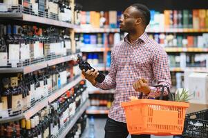 africano americano homem dentro mercearia loja comprando vinho foto