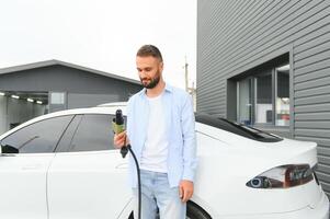 homem cobrando elétrico carro de a casa. foto