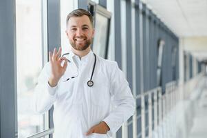 jovem masculino médico dentro uma corredor do uma geral hospital foto