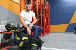 bombeiro mudando roupas e fixação dele capacete dentro fogo departamento foto