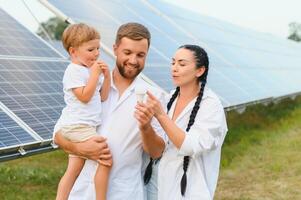 feliz família perto solar painéis. alternativo energia fonte foto