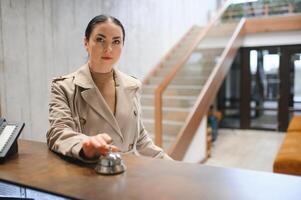 elegante o negócio mulher com viagem carrinho bagagem dentro hotel lobby foto