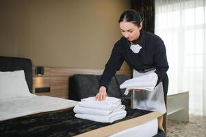 empregada fazer cama dentro hotel quarto enquanto dobrando toalhas foto