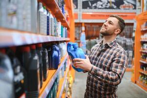 homem compra automóvel produtos químicos dentro a auto partes loja foto