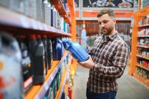 homem compra automóvel produtos químicos dentro a auto partes loja foto