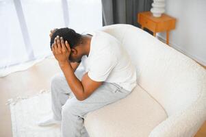 chateado afro-americano homem apertando cabeça com mãos, contorcendo-se dentro dor, sofrimento a partir de dor de cabeça às lar, cópia de espaço foto