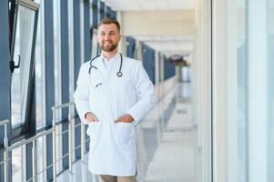 retrato do bonito jovem médico em hospital corredor foto