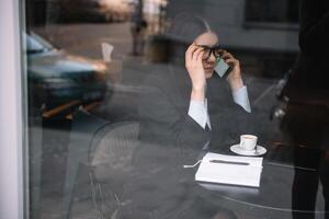 jovem empresária falando em a telefone dentro café fazer compras foto