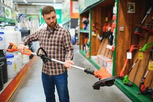 feliz cliente com elétrico gramado aparador dentro mãos às jardim equipamento loja foto