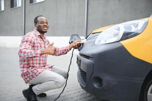 à moda homem inserções a cobrando cabo para dentro a tomada do elétrico carro foto