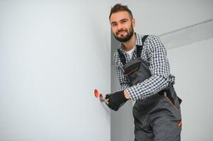 eletricista dentro uniforme montagem elétrico tomadas em a branco parede dentro de casa foto