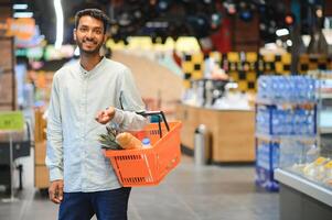 retrato do bonito jovem indiano homem em pé às mercearia fazer compras ou supermercado, fechar-se. seletivo foco. foto