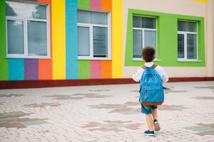 pequeno Garoto indo costas para escola. criança com mochila e livros em primeiro escola dia. costas visualizar. escola conceito. costas para escola. foto