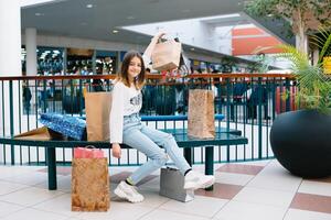 varejo, gesto e venda conceito - sorridente Adolescência menina com muitos compras bolsas às shopping center. compras conceito foto