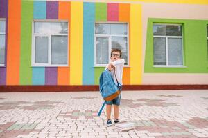 fofa estudante dentro branco camisas e uma óculos com livros e uma mochila. costas para escola foto