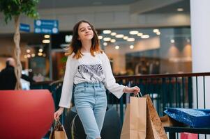 varejo, gesto e venda conceito - sorridente Adolescência menina com muitos compras bolsas às shopping center. foto