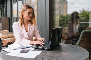 bem sucedido o negócio mulher com financeiro documentos em pé perto uma ampla janela dentro uma moderno escritório foto