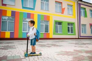 Garoto vai para escola em uma lambreta. crianças costas para escola scooter.childschool equitação uma lambreta. costas para escola. feliz crianças. feliz infância estilo de vida. aluna vai para escola foto