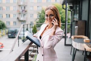 o negócio mulher em a telefone às escritório. jovem o negócio mulher tendo telefone ligar às a escritório. sorridente o negócio mulher. bonita jovem o negócio usando Smartphone às a loft escritório. foto