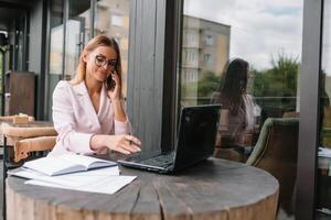 bem sucedido o negócio mulher com financeiro documentos em pé perto uma ampla janela dentro uma moderno escritório foto