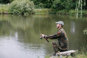 pescaria dentro rio.a pescador com uma pescaria Cajado em a rio banco. homem pescador pega uma peixe pique.pesca, fiação carretel, peixe, breg rios. - a conceito do uma rural fugir. artigo sobre pescaria foto