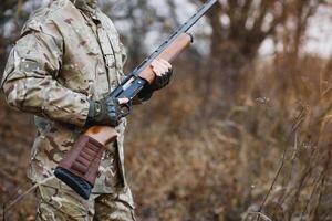 caçador bonito cara com arma. caçador gastar lazer Caçando. Caçando equipamento. brutal masculino passatempo. homem observando natureza fundo. caçador aguarde rifle. segurança medidas. natural meio Ambiente foto