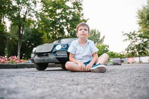 fofa Garoto dentro equitação uma Preto elétrico carro dentro a parque. engraçado Garoto passeios em uma brinquedo elétrico carro. cópia de espaço. foto