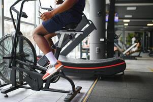 atraente homem às saúde clube, exercício em bicicleta foto